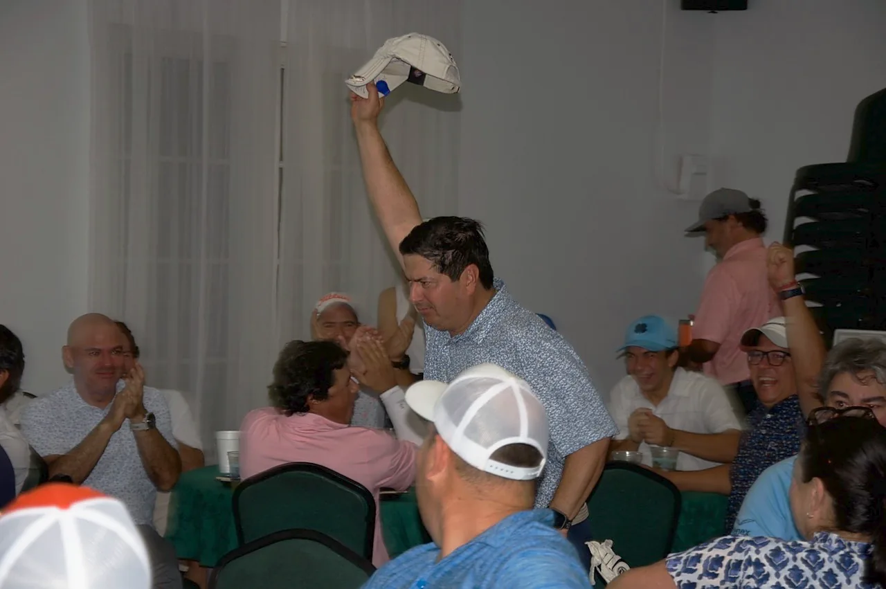 A winner raising his cap as the room applauds during the awards