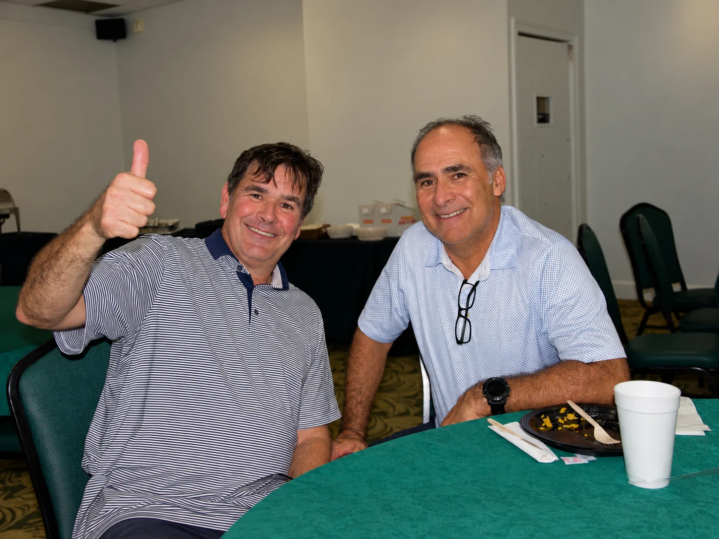 Two players giving a thumbs up at their clubhouse table