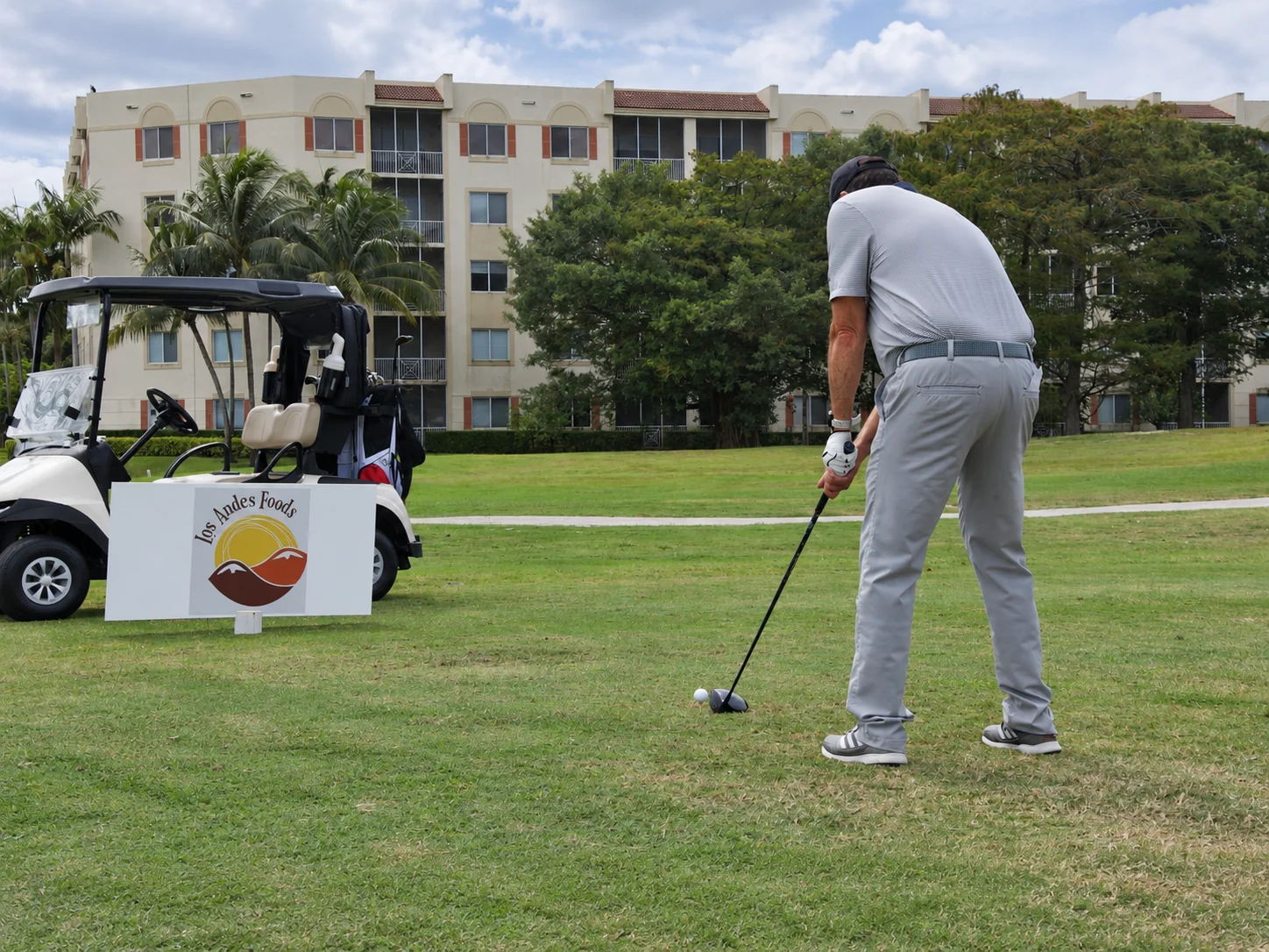 A player driving from the tee beside the Los Andes Foods sign