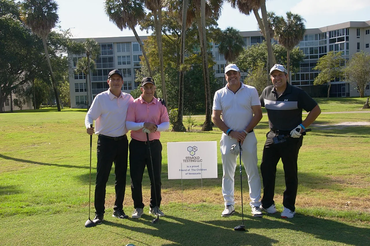 A foursome at the 911 Mold Testing LLC sponsor sign
