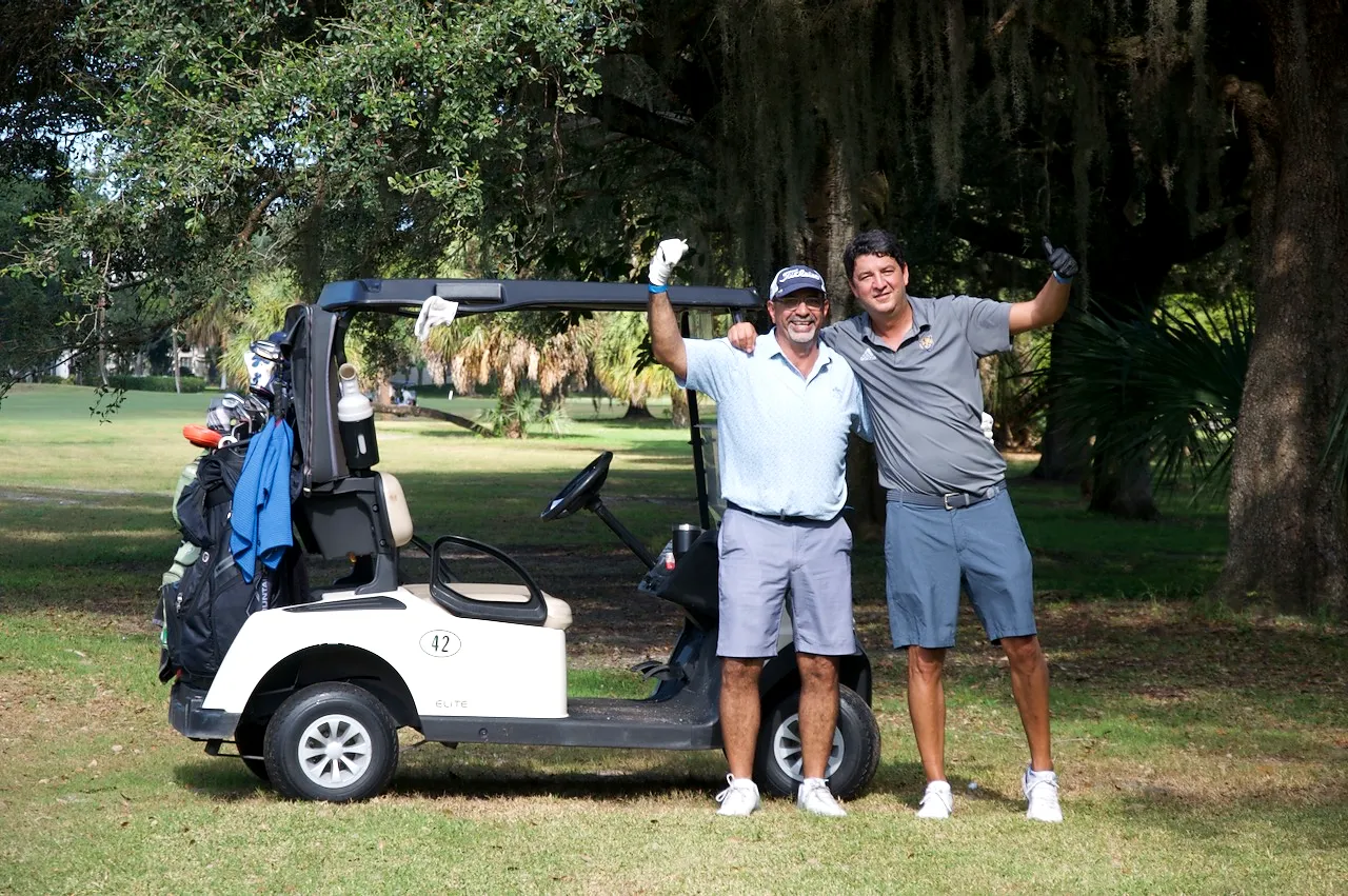 Two players celebrating beside cart 42 under the oaks