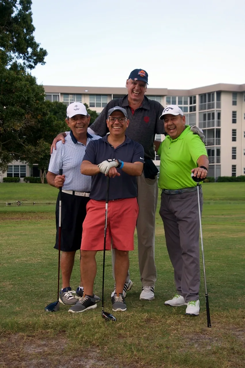 Four players laughing together on the fairway at dusk