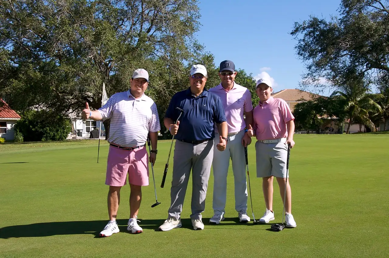 A foursome giving a thumbs up on the putting green