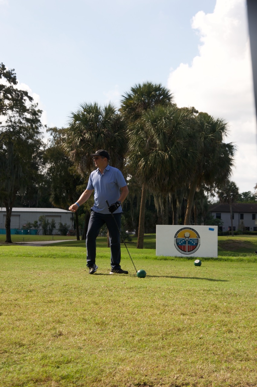 A player at the tee box beside the tournament sign